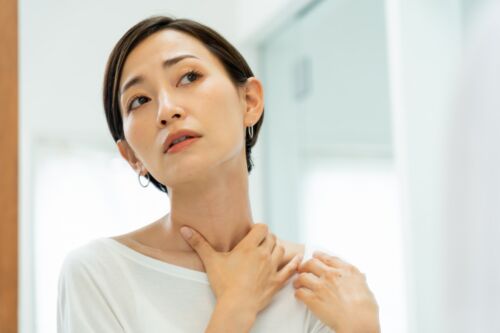 首もとを気にする女性のイメージ